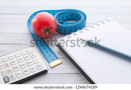 Measuring tape and calculator with juicy tomato, concept of healthy eating and slimming