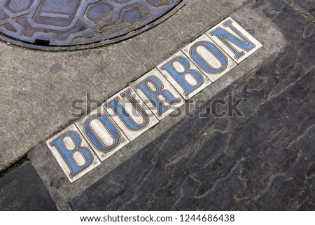 Bourbon Street tile signage on street next to manhole in New Orleans, Louisiana French Quarter