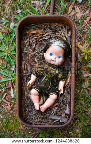 Creepy Grungy Old Baby Doll Laying in a Rusted Metal Wagon