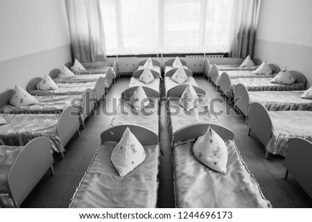 Cots in the kindergarten. Orphanage or boarding school. Beds in a boarding school or in an orphanage. Royalty-Free Stock Photo #1244696173