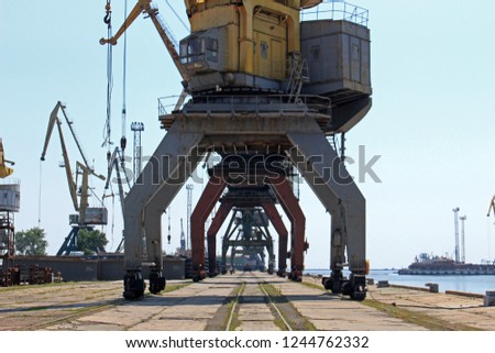 A colorful photograph of giant aging cranes on the Ukrainian seaside in an industrial shipyard.