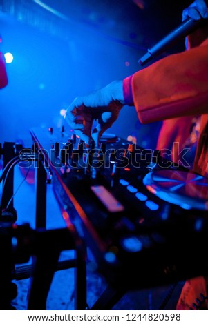 Dj mixes the track in the nightclub at party. In the background laser light show