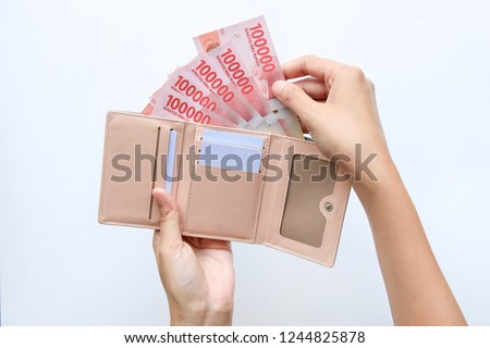 Indonesian hand woman take out showing rupiah money from pink wallet Royalty-Free Stock Photo #1244825878