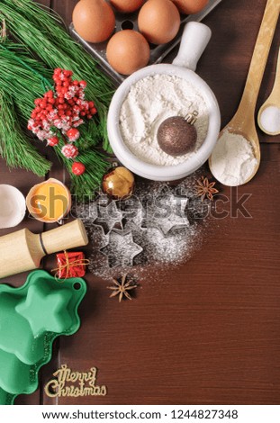 Christmas baking cake background. Ingredients and tools for baking - flour, eggs, silicone molds in the shape of a Christmas tree, and a rolling pin on a wooden background. With free text space.