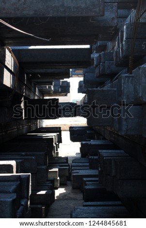 An interior closeup photograph of stacks of steel beams which are waiting in the dockyard.