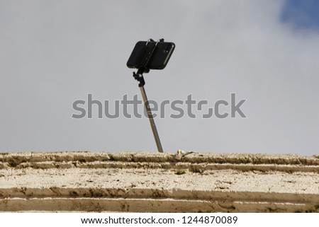 A selfie stick with no visible trademark appearing from above a wall on the Spanish Steps in Rome, Italy
