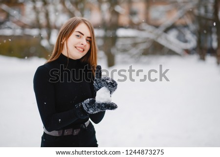 Cute girl in a winter park. Woman have fun with snow