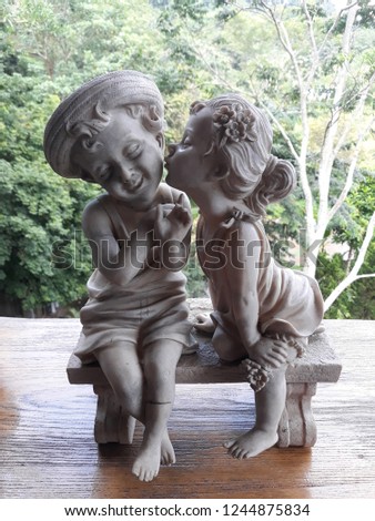 Statue of child girl and boy hugging kisses. Vintage style photo.