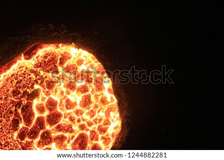 A closeup, off center, birds eye view photograph of molten steel in a large crucible at a steel factory.