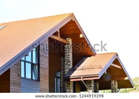 Wooden house on green grass with blue sky background and the sun's rays. Natural photo.