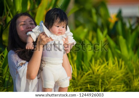 young attractive and happy Asian Japanese woman playing sweet with baby girl  enjoying relaxed together at summer holidays resort swimming pool in mother and little daughter tropical vacation trip