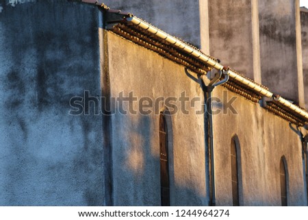 Outdoor abstract view of an old facade of an abandoned church in France. Warm colors with light on an ancient stone wall with pattern of windows. Picture taken in the evening during autumn season.