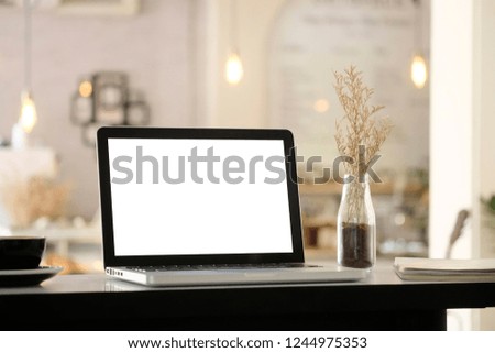 Mockup laptop computer on blur cafe background.
