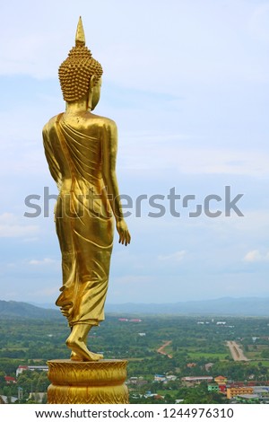Nine metres high golden Buddha image in walking posture of Wat Phra That Khao Noi, a hilltop historic temple in Nan Province, Thailand