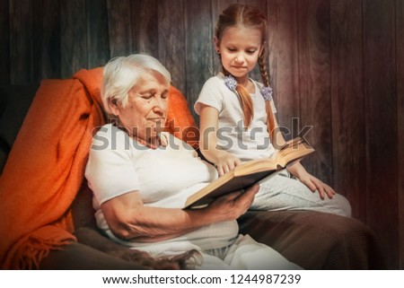grandmother and granddaughter in a chair, reading a book together, precious time with loved ones