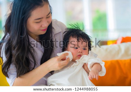 lifestyle candid portrait of young happy and cute Asian Korean woman playing and holding sweet expressive baby girl sitting at holidays resort in mother and little daughter love concept