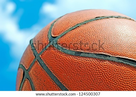 close up of a orange basketball under a blue sky