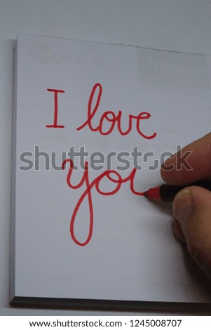 hand writing with red pen I Love You on white paper