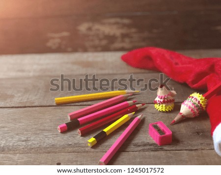 Color pencil trash, crayon, and Red christmas hat, like a Santa Claus, on old wood, dark tone, with copy space. Selective focus. Decorative series for merry christmas and new year festival.