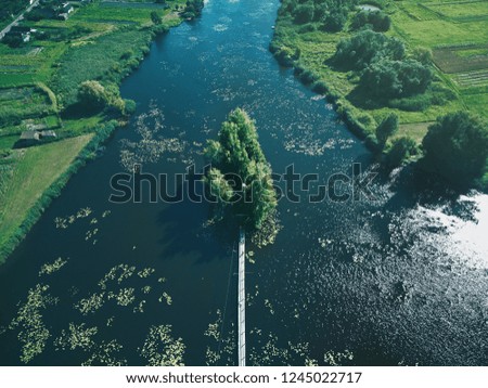 House On Lake. Bridge Leading To House With Green Trees On River Aerial View