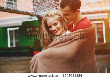 a young and lovely couple standing near a building with a blanket