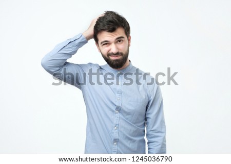 Spanish young man with black beard thinking, scratching his head. I am not sure or who know concept. I am not an expert in this matter. Royalty-Free Stock Photo #1245036790
