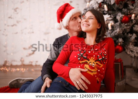 Picture of loving man and pregnant woman on background of Christmas decorations