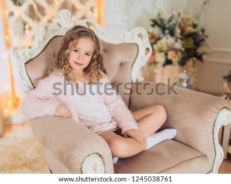 Beautiful baby girl near a Christmas tree with gifts