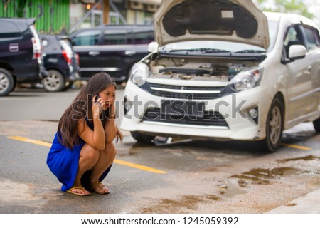 young desperate and upset Asian Chinese woman in stress stranded on street suffering car engine failure having mechanic problem calling to insurance assistance service on mobile phone for help
