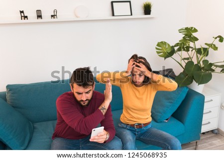 Two young people, couple fighting at home. Girl angry and stressed out puts her hands on her head, boyfriend cheated on girlfriend. Cheating boyfriend. Relationship problems.