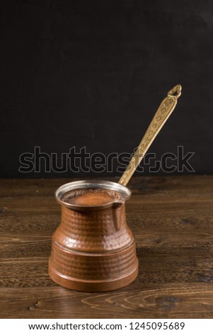 Hot coffee in Turkish copper pot on wooden table