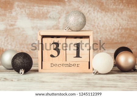 Hand changing wooden calendar with different New Year decorations, blurred background