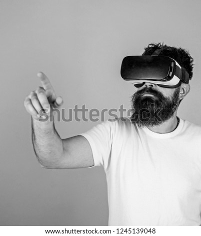 Man with hipster beard in VR glasses using digital touch screen. Bearded man interacting with cyber space through virtual reality interface. Computer geek with nerdy beard testing new tech toy.