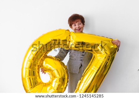 Senior woman celebrating her birthay at home with cake, ballons and confetti