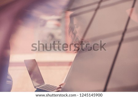 Business woman sitting in the back seat of an elite car holding a laptop.