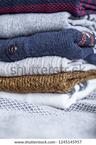 A stack of woolen sweater on the bed. Home atmosphere, winter clothing.
