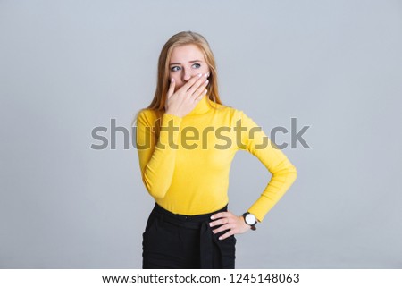 Beautiful blonde woman standing on a gray background