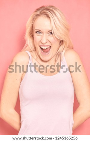 one young woman headshot, 20-29 years old, long blond hair. Shot in studio on pink background. Looking up to camera, looking so amazingly excited that she will explode.