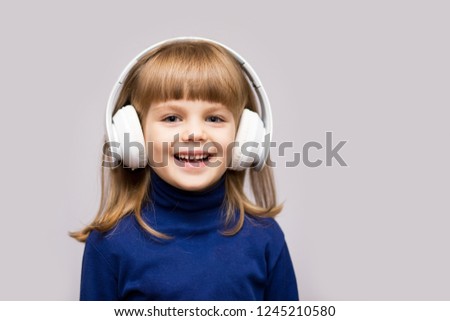 Happy smiling child enjoys listens to music in headphones over white background