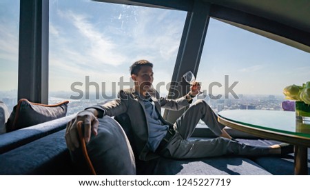 Man tasting his wine and seeing a view of the city