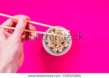 dices in white bowl with chopsticks on magenta background