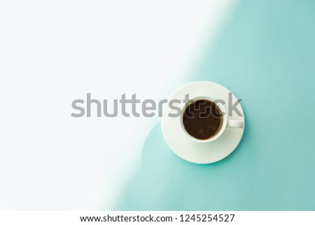 Cup of steaming coffee on seafoam green table, top view. Abstract photo of hot espresso drink on pale blue-green background