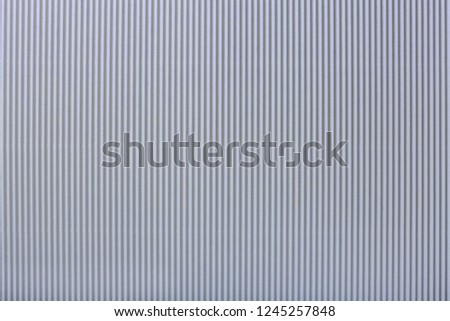 Texture of corrugated light gray paper, macro. Striped pattern of silver cardboard background, closeup.