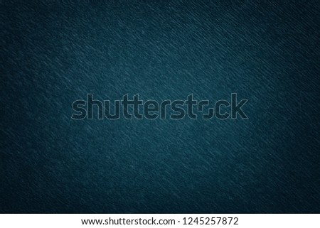 Textural of navy blue background of wavy corrugated paper, closeup. Structure of wrinkled crepe dark denim cardboard with vignette.