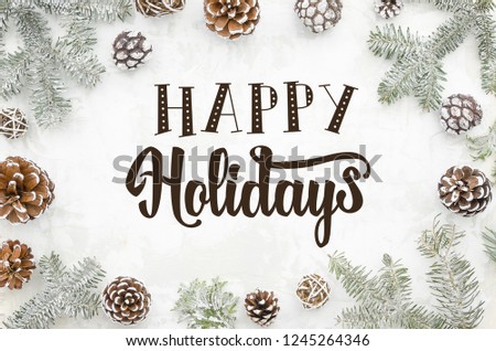 Greeting card happy holidays hand lettering on winter background with cones and fir branches. Flat lay.