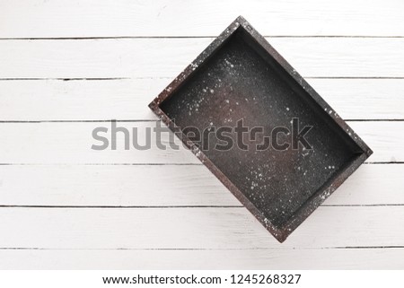 Old wooden black box. On a white wooden background. Top view. Free copy space.