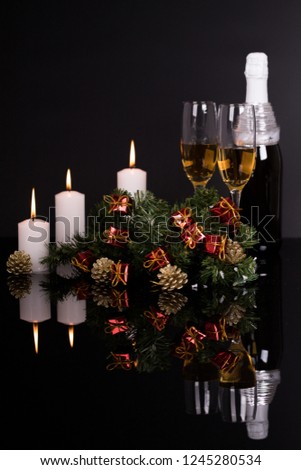 Two wine glasses with champagne, candles and Christmas ornaments on a black background with reflection. Copy space. Merry Christmas and Happy New Year, background