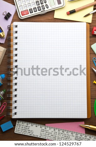school supplies and checked notebook on wood background