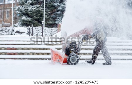 Snow-removal work with a snow blower. Man Removing Snow. heavy precipitation and snow piles Royalty-Free Stock Photo #1245299473