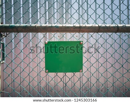 Mesh wire fence with blank green sign for your custom texts.